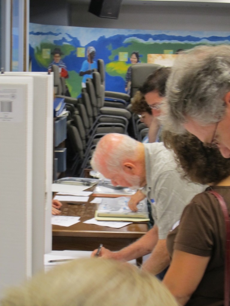 People filling out metadata forms infront of a photo display.