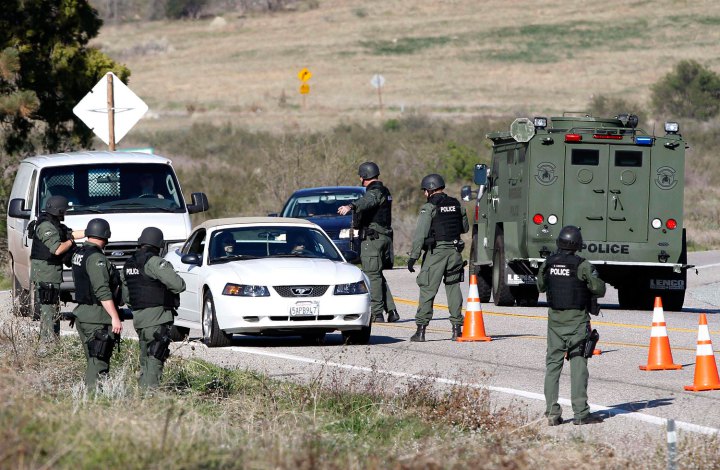 Armed police officers search vehicles driving south in Yucaipa during the manhunt for fugitive former Los Angeles police officer Dorner